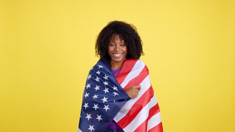 smiling african american woman wrapped in american flag on yellow background