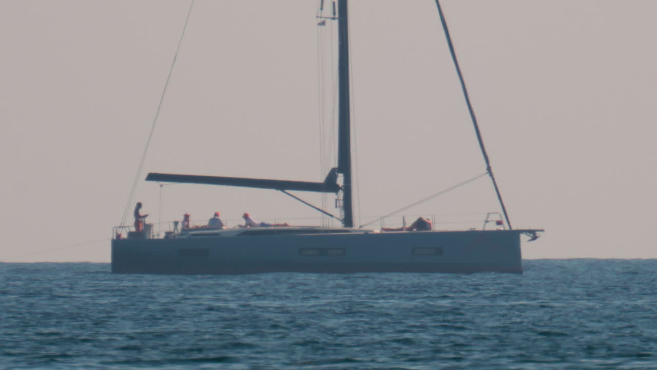 Una lussuosa barca a vela con diverse persone a bordo che naviga tranquillamente nel Mar Mediterraneo calmo