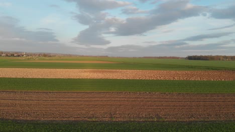 Aerial-landscape-view-of-cultivated-agricultural-fields-on-cloudy-day-in-spring