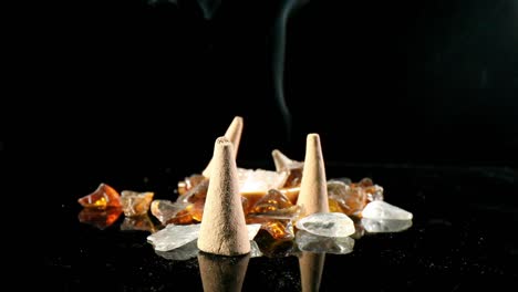 Static-shot-of-unlit-incense-cones-in-a-decorative-rock-garden,-a-lit-cone-w--smoke-billowing-in-the-back