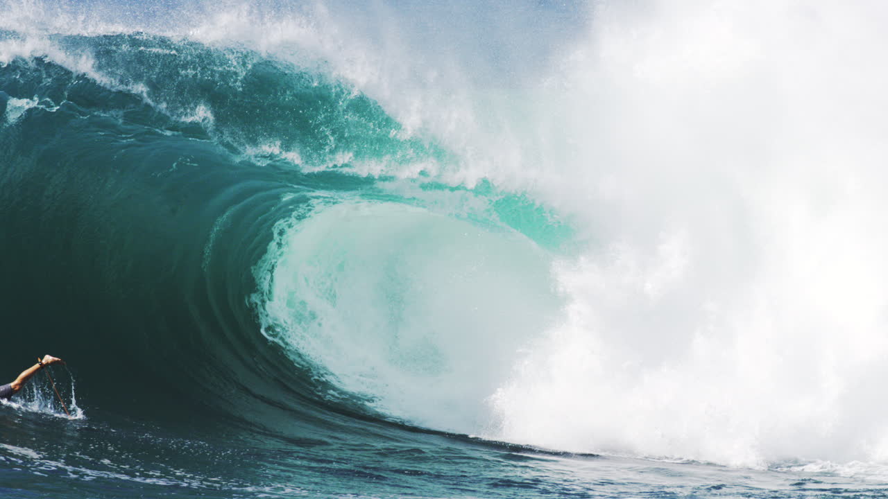 Crystal blue wave rolls cleanly, white mist sprays across soft glowing textures