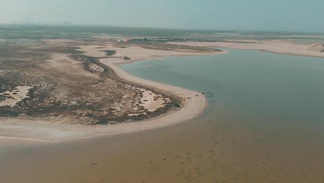 Luftflug-über-Den-Salzsee-Mit-Gleitschirm,-Der-In-Der-Ferne-über-Die-Küste-Von-Karatschi-Fliegt