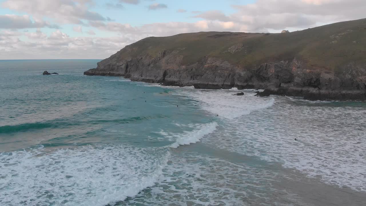 The stunning aerial shot of Perran Sands during sunset, surfers are in the water waiting to catch a perfect wave