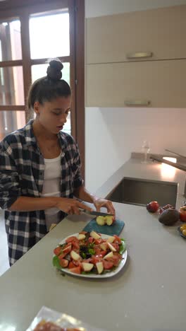 una adolescente preparando una ensalada en una cocina.