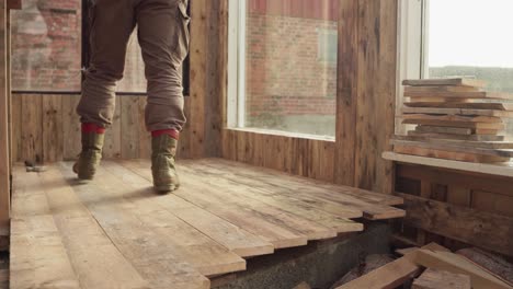 man fastening wooden flooring inside greenhouse. static shot