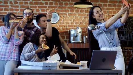 cheerful colleagues taking selfie with pizza