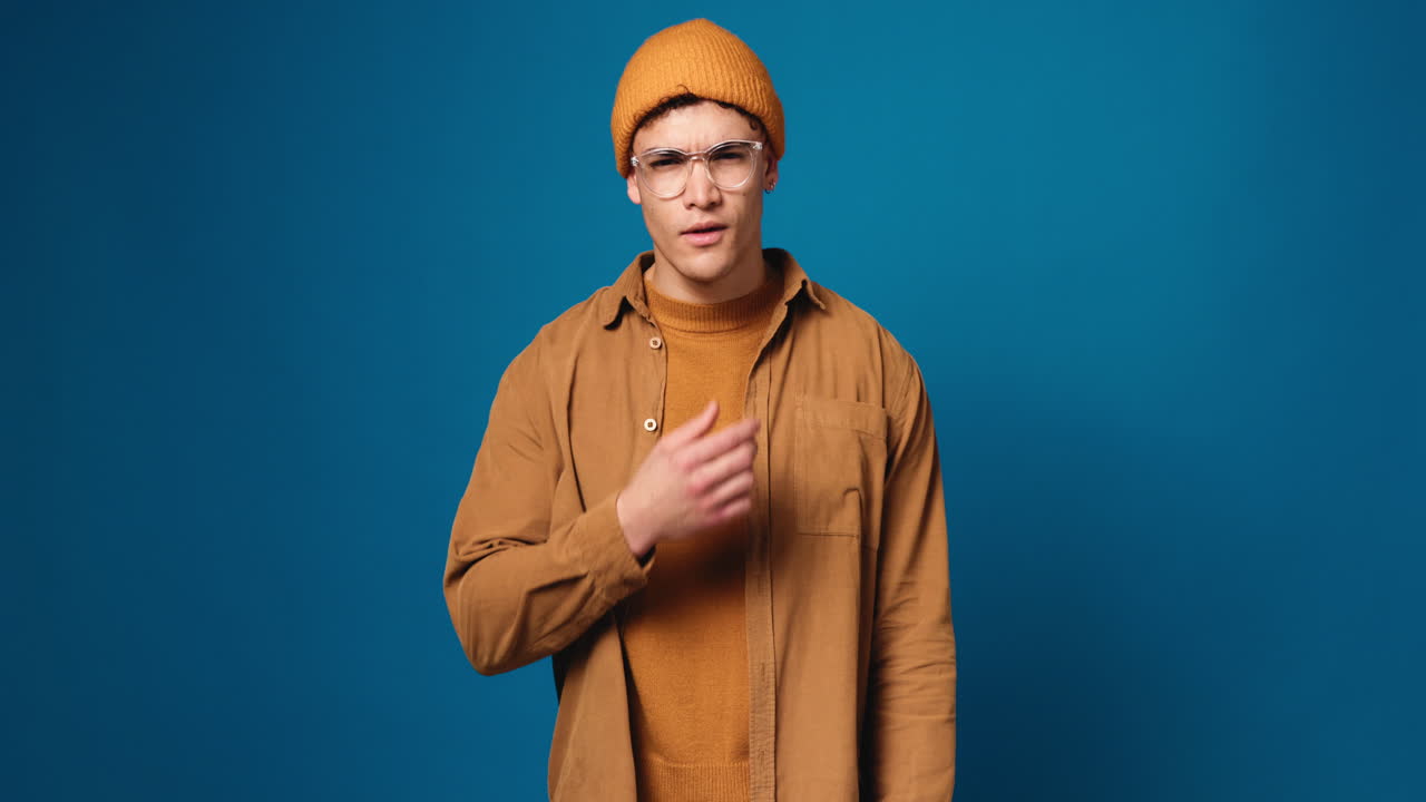 Portrait of a Man with Glasses and Hat on Blue Background