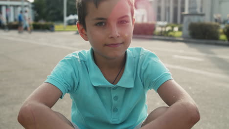 cute boy sitting in amusement park. close up relaxed teen boy outside