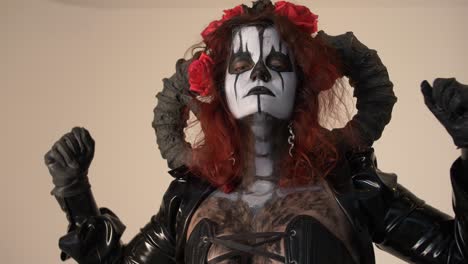 catrina cosplay girl with hands crossed on her chess and domina outfit and light background, medium close up