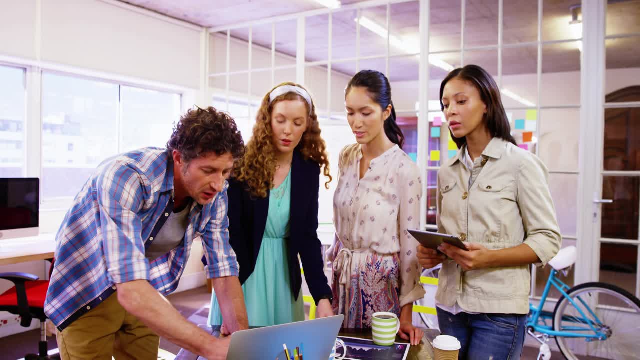 Man pointing while team tapping tablet and floating social icons rising around laptop for marketing