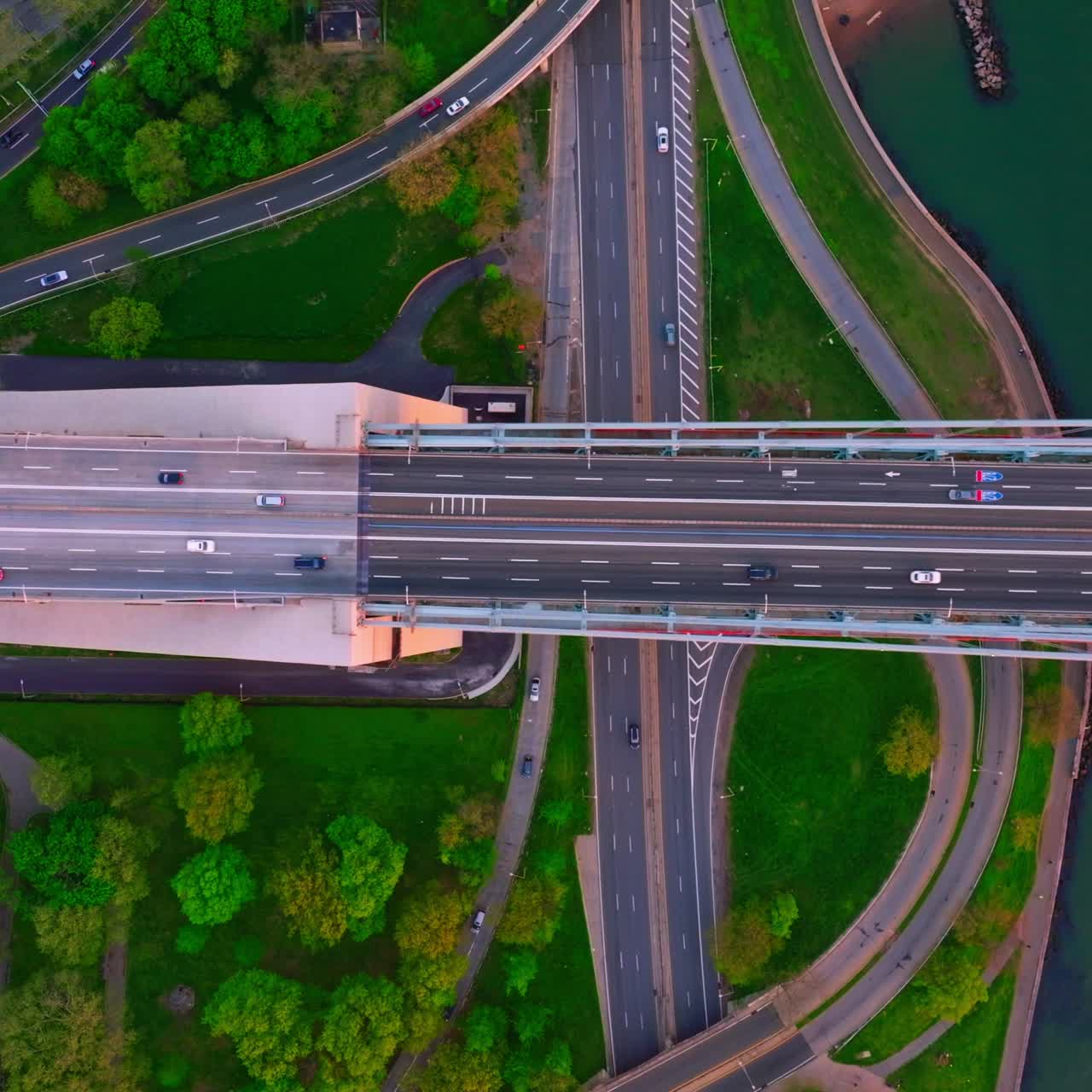 Diverse speed roads going in different directions. Cars going quickly along green areas and huge bridge