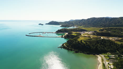 Boat-pier-in-the-sunset-on-Limestone-Bay-in-New-Zealand,-aerial-forward