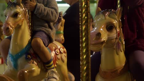 carousel horses moving with kids hopped on in slow motion, closeup