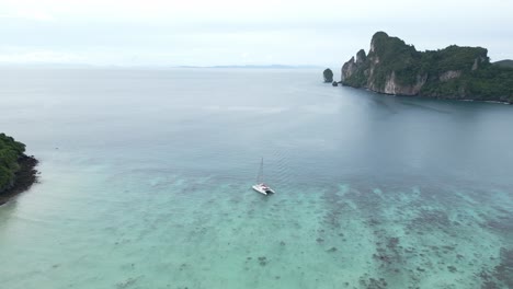 Vista-Aérea-Acercándose-Al-Catamarán-Flotando-En-Las-Aguas-Azules-Del-Océano-De-Tailandia