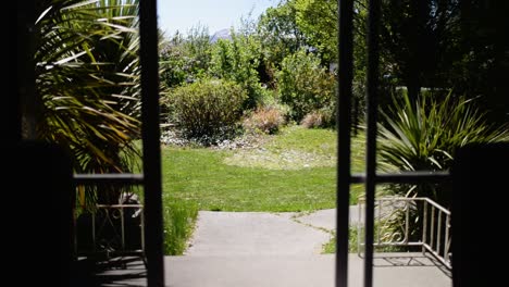 saliendo por una puerta de cristal hacia una veranda bajo el sol en un ventoso día de primavera