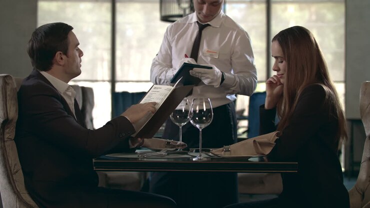 красивый мужчина читает меню в ресторане. деловая пара заказывает еду в кафе