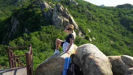 Mädchen,-Das-Nach-Einer-Wanderung-Auf-Den-Felsbrocken-Liegt-Und-Das-Warme-Sonnenlicht-Mit-Blick-Auf-Den-üppigen-Wald-Am-Gwanaksan-berg-In-Seoul,-Südkorea-Genießt