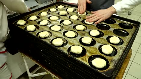 bakers lay out the dough buns on a baking tray