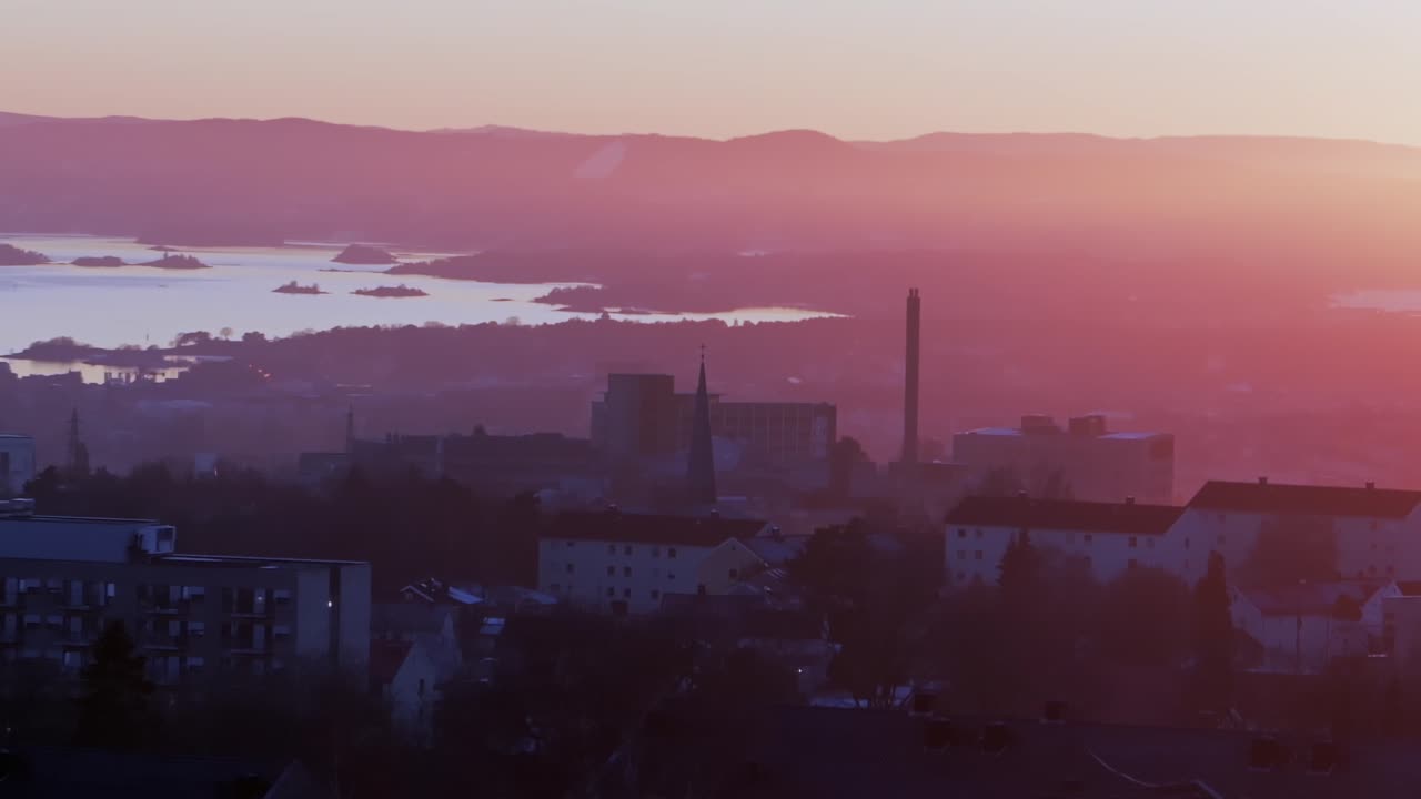Downtown Oslofjord Olso city Norway Norge aerial drone view inner coastline Hovedøya Lindøya islands Norwegian arctic vibrant pink hue sunset apartment church buildings parallax circle left zoom