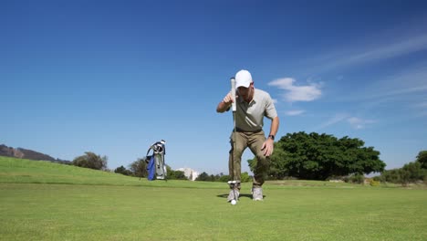 caucasian male golfer kneeling on a golf course on a sunny day