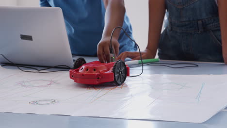 close up of two students programing robot vehicle in after school computer coding class