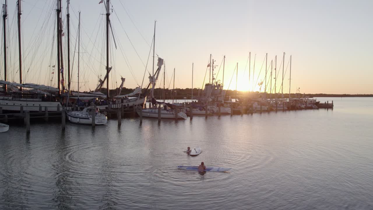 Vista aerea dell'IJsselmeer al tramonto con villaggio, SUP e yacht a Makkum, Paesi Bassi, con luce mozzafiato, atmosfera calma, riprese drone di alta qualità che evidenziano la bellezza naturale