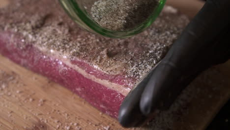 chef wearing black food grade gloves is salting a wonderful piece of beef brisket, prepping it before smoking it