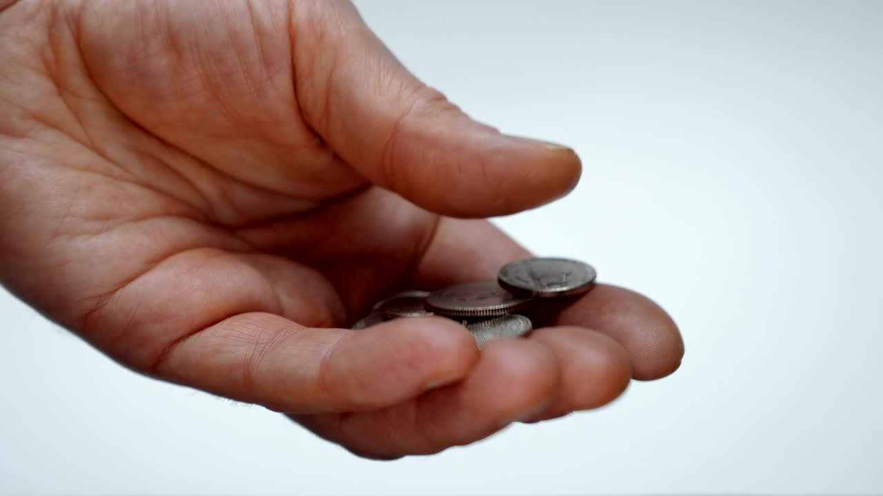 un hombre se toma su tiempo examinando una pequeña cosa en su mano, tratando de encontrar una moneda correcta