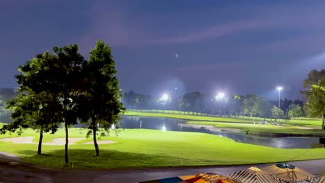 illuminated golf course with trees and water