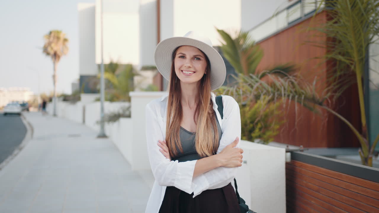 mujer con un sombrero blanco, sonriendo en una calle de la ciudad