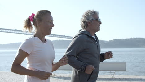 happy runners training together and smiling when jogging