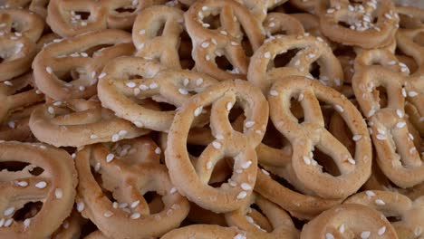 una pila de pretzels salpicados de sésamo giran en una mesa giratoria. comida rápida no saludable pero deliciosa.