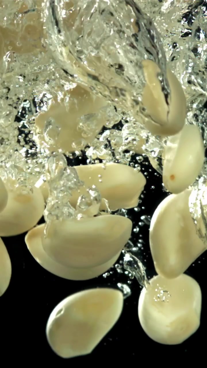 Spicchi d'aglio pelati che cadono nell'acqua con bolle