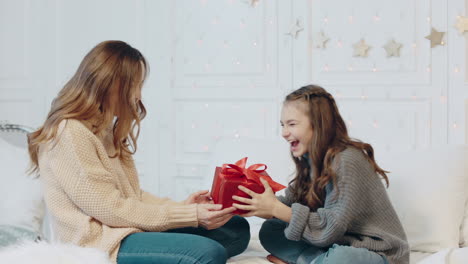 smiling girl closing eyes in luxury house. pretty mother presenting gift