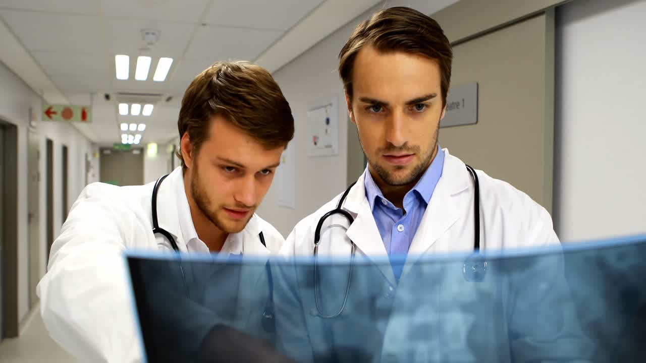 Doctors examining x-ray report in corridor