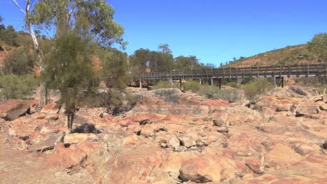 panning shot left to right of a dry riverbed, trees and a bridge, aerial