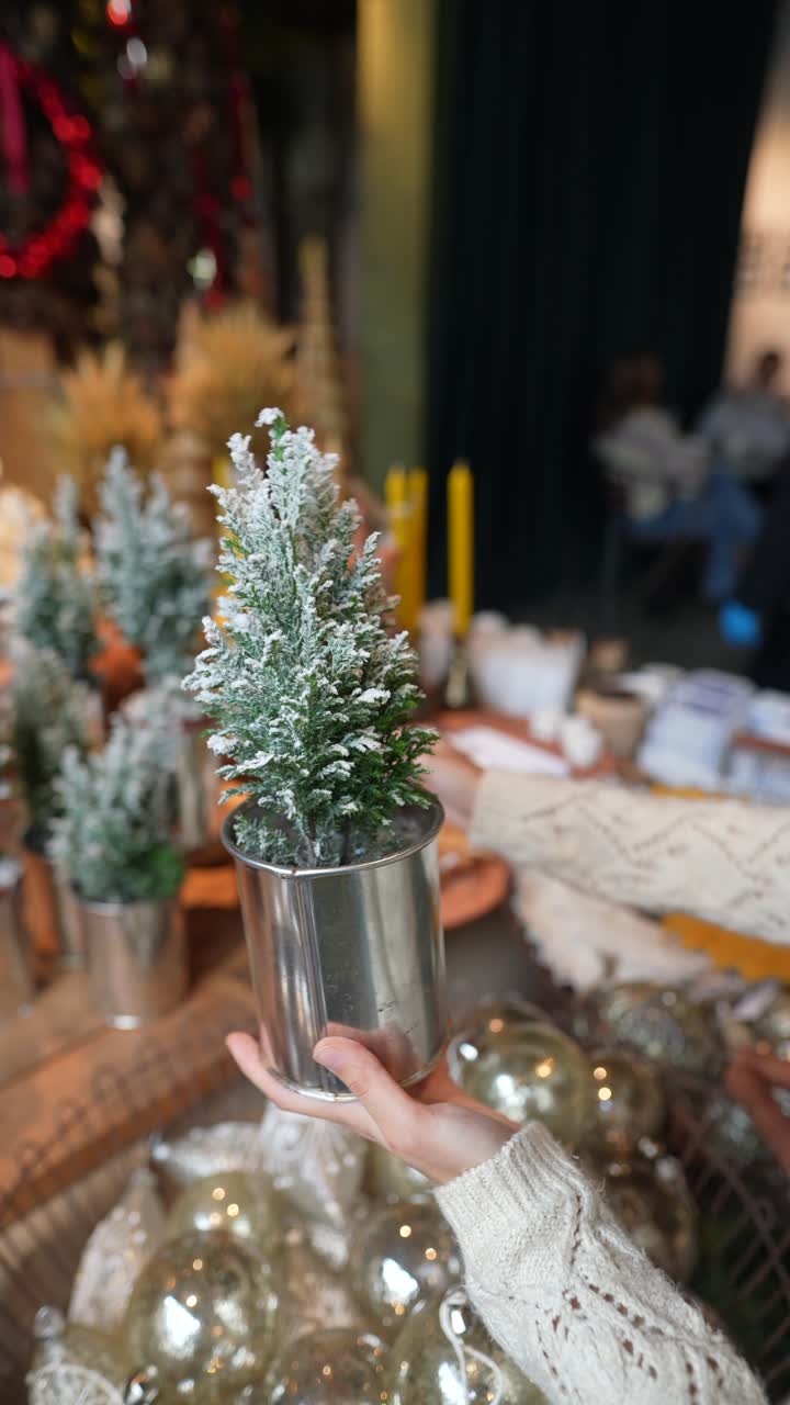 mujer decorando un pequeño árbol de navidad en una lata de lata en un mercado de vacaciones