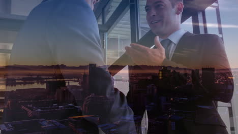 composición digital de dos hombres de negocios caucásicos que se dan la mano en la oficina contra el paisaje urbano nocturno