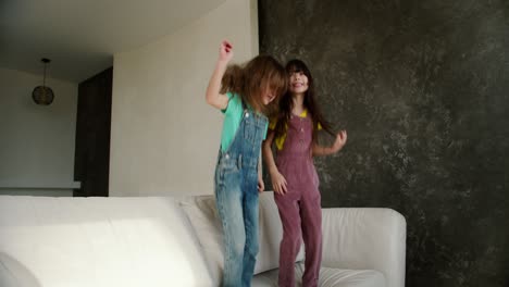 Two-little-girls-sisters-are-having-fun-to-jump-on-the-white-sofa