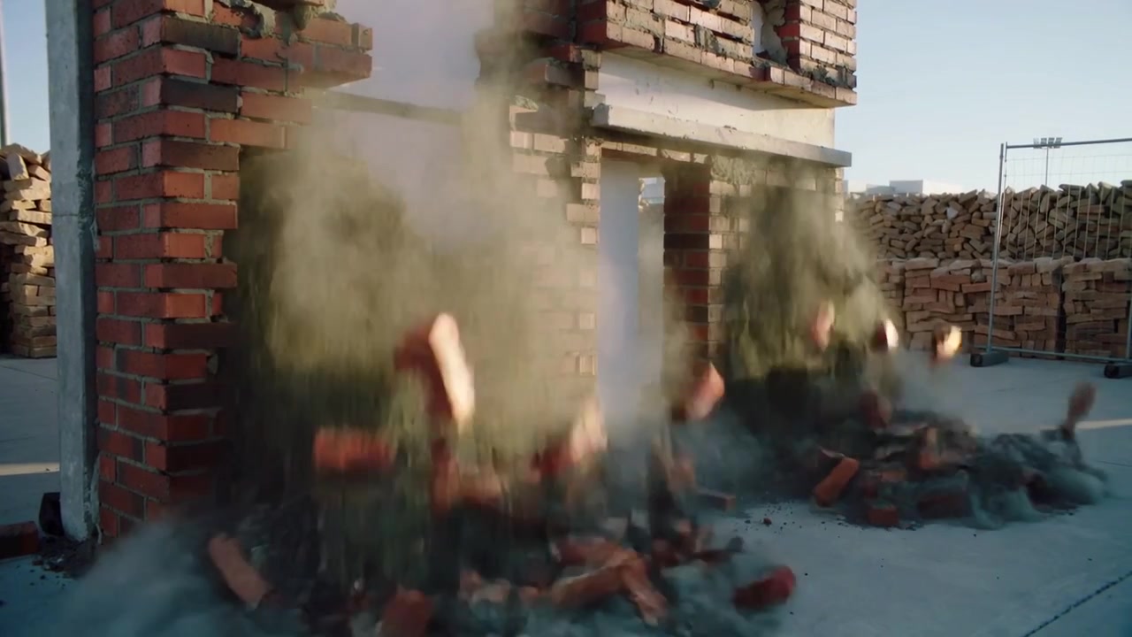 Collapsing brick facade after center base failure in yard, ejecting red clay bricks and green dust
