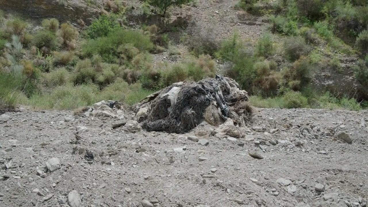Medium shot of plastic bags, tarps and other kinds of garbage coming from intensive farming and greenhouses abandoned on the bed of a river in Spain.