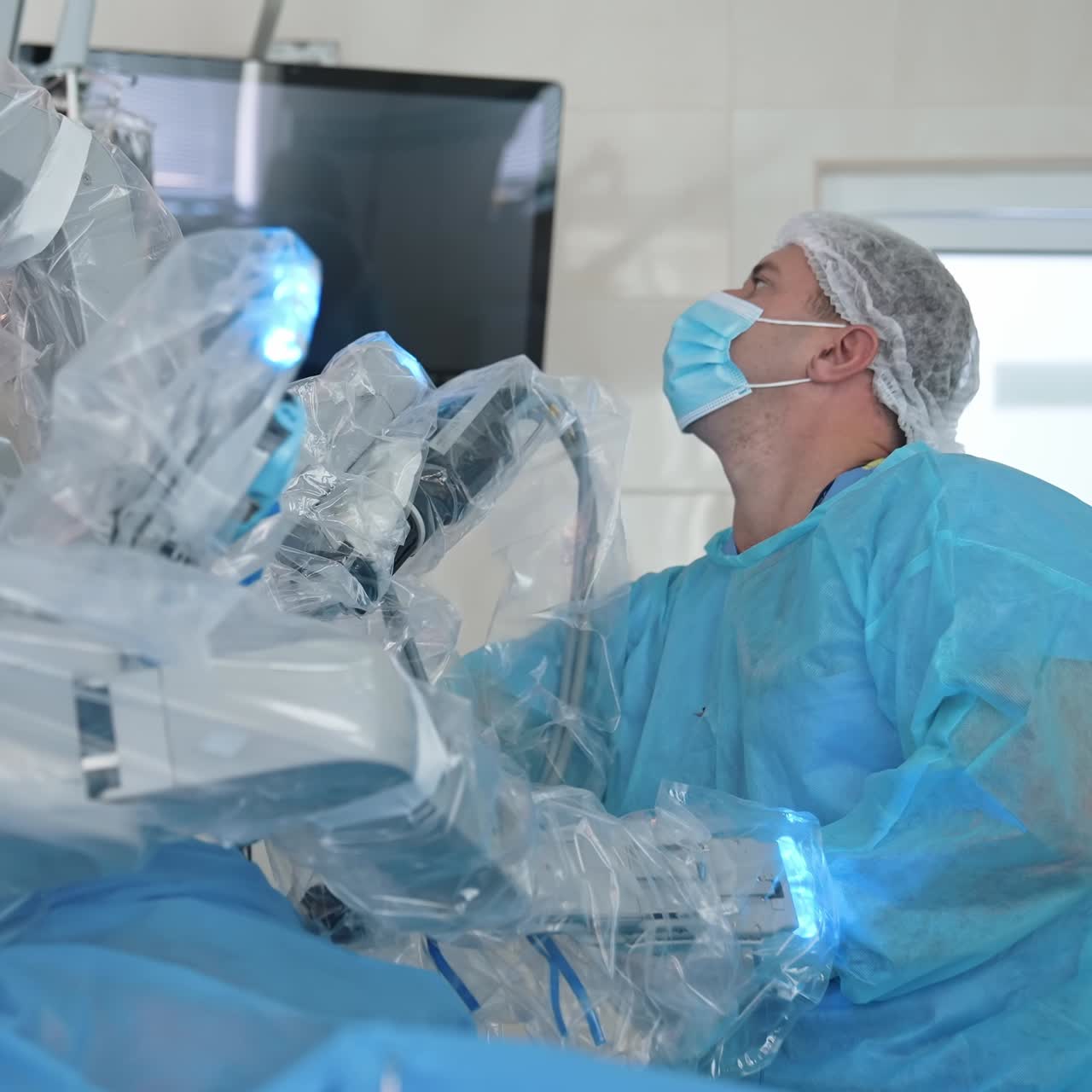 Futuristic robot in operating room. Doctor near modern medical device. Robotic surgery on the background of medical monitor showing microsurgery process