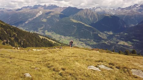 drone shot flying backwards of a couple man and women standing on a mountain looking over a valley in switzerland in 4k