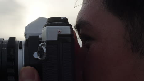 extreme closeup of a young man with camera taking photos of nature