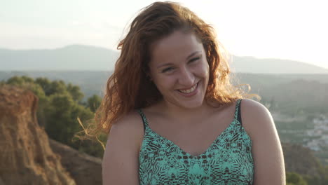 portrait of a smiling woman with red hair outdoors