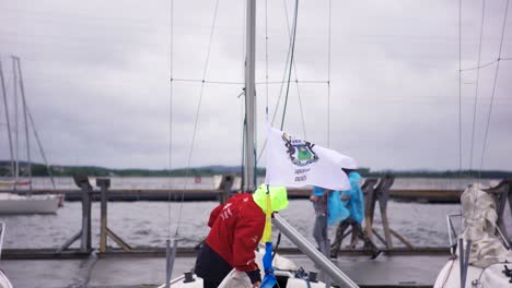 sailors preparing sailboats at a marina on a cloudy day