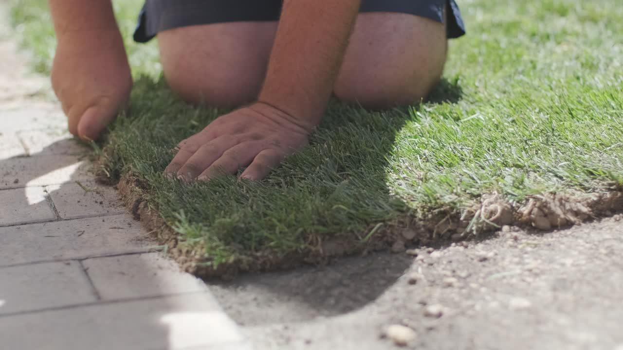 hombre colocando césped en el jardín del patio trasero para la instalación de césped y proyecto de jardinería, centrado en la mejora del hogar y el mantenimiento al aire libre para un césped fresco y verde en un patio residencial