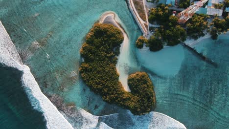 green island with white sand beach waves and blue lagoon