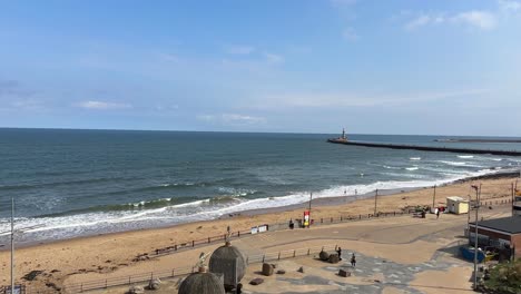 scenic view of roker beach and sunderland pier with waves crashing on shore and sunny sky
