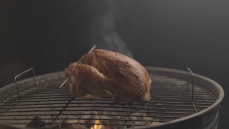 chicken getting grilled on coal and fire with smoke coming up with black background shot raw and 4k eye level